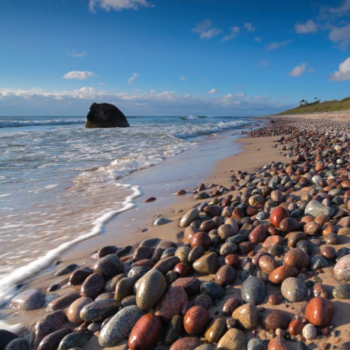gotska-sandoen-kiesel-meer Nasse Kieselsteine in verschiedenen Rot-, Orange- und Grautönen glänzen am Strand des Gotska Sandön Nationalparks.